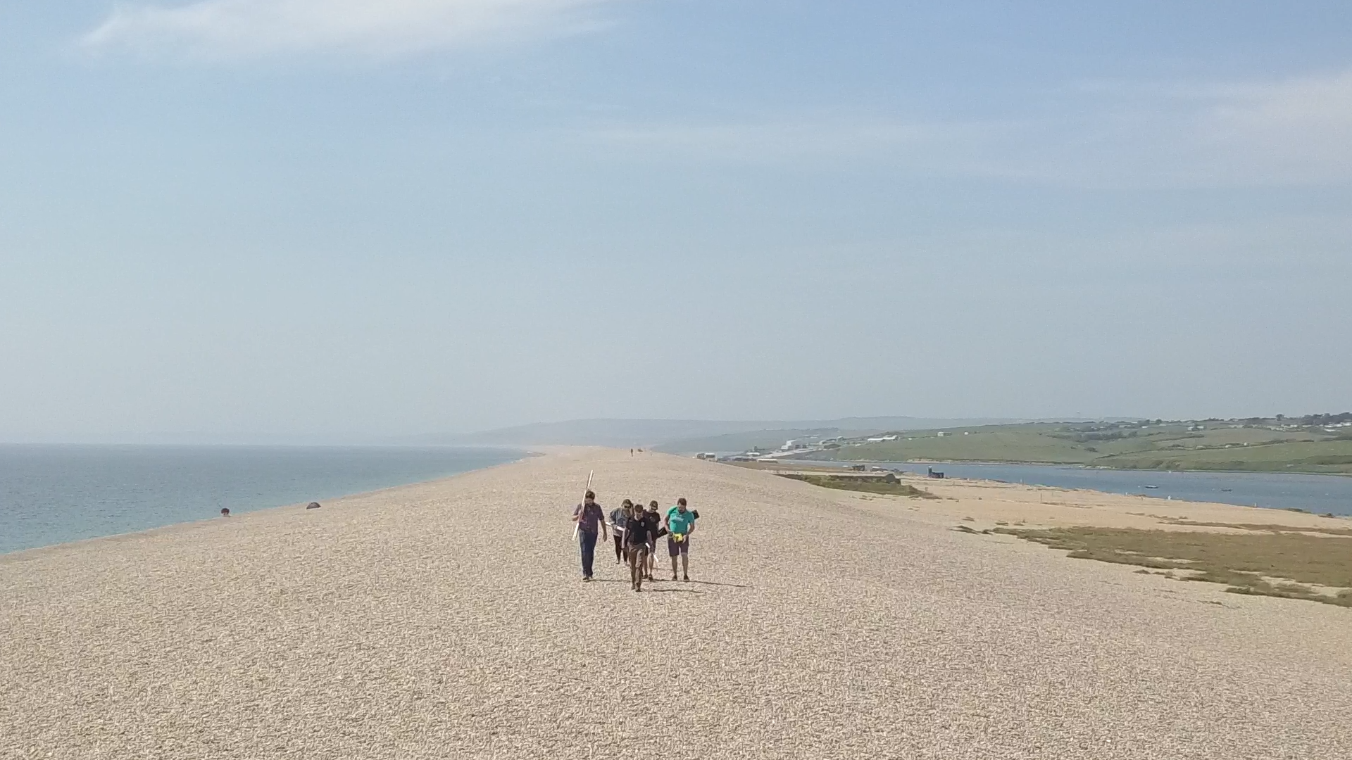 Group of students walking on Chesil Beach carrying equipment relating to Marine Ecology and Conservation