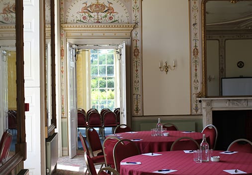 The Pengelly Room with circular tables, red table cloth and set for a conference, view towards the Whatmoor Room
